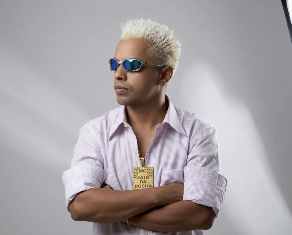 MC Jair da Rocha de camisa clara e braços cruzados